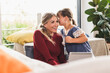© Westend61 - Girl whispering into mother's ear at home