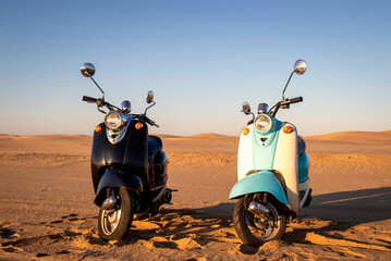 Two Retro scooters at sunset in the golden sand of the Namib Desert