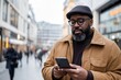 © vasyan_23 - Mature african male in urban setting using smartphone on a cold day