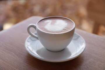 Wall Mural - Cup of aromatic coffee on wooden table in cafe, closeup