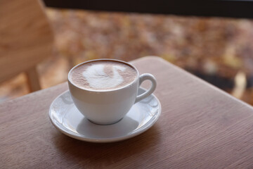 Wall Mural - Cup of aromatic coffee on wooden table in cafe, closeup