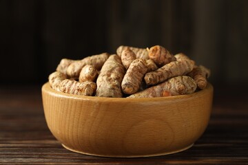 Canvas Print - Tumeric rhizomes in bowl on wooden table, closeup