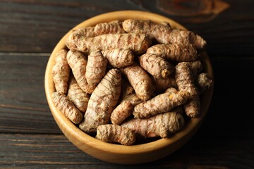 Canvas Print - Tumeric rhizomes in bowl on wooden table, closeup