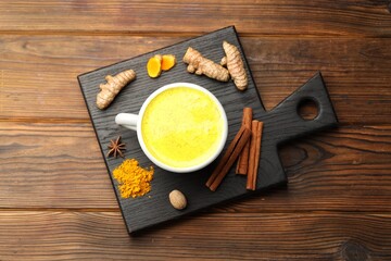 Wall Mural - Tasty turmeric latte in cup and spices on wooden table, flat lay