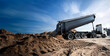 © Кристина Пахомова - A dump truck is in the process of dumping sand onto a dirt road