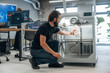 © standret - Sitting and holding printed product. Man is in the office with 3d printer