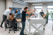 © standret - Big screen with code on the wall. People are in the office by the 3d printer