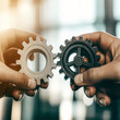 © Vasili - Two hands connecting gears, symbolizing teamwork, collaboration, and synergy in a professional setting. Focus on the intricate detail of gears fitting together.