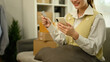 © saltdium - A Close-up image of a woman happily completing an online purchase using her phone and credit card with Stacked parcels nearby, e-commerce, secure digital payments, and fast delivery