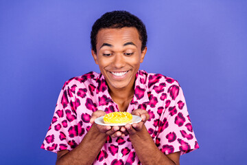 Smiling man holding plate with dessert in vibrant stylish attire against purple background