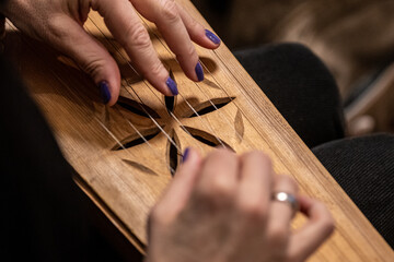 Wall Mural - Fingers of a girl playing kankles, Lithuanian plucked string instrument belonging to the Baltic box zither family known as the Baltic psaltery, in Latvian kokles, Estonian kannel, Finnish kantele