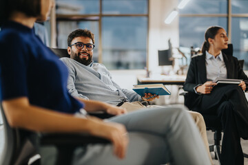 Wall Mural - A group of diverse business professionals engage in a casual office meeting, discussing ideas and sharing documents. The setting promotes collaboration and teamwork among the employees.