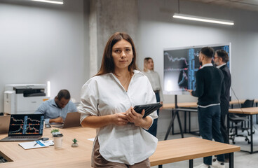 Wall Mural - Woman is looking at the camera. Group of office workers are indoors together