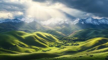 Wall Mural - Lush green hills with snow-capped mountains under dramatic sky and sun rays. Scenic landscape and nature beauty concept