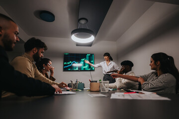 Wall Mural - Team of diverse professionals collaborating in a business meeting, analyzing data on a screen, fostering teamwork and growth. The setup highlights a modern, innovative workspace designed for