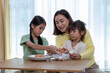 © Washburn - Happy family, father, mother and daughter are having fun peeling eggs in the living room