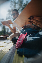 Canvas Print - Two friends enjoying a picnic in the park, sketching on paper while surrounded by trees and sunlight, fostering creativity and companionship.