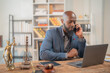 © Tj - African American lawyer sitting at desk, working on laptop and speaking on smartphone, with Lady Justice statue and gavel prominently displayed in the foreground