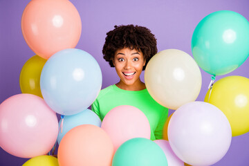 Wall Mural - Photo of cheerful positive wavy cute nice charming black girl surrounded with air balls smiling toothily isolated over violet pastel color background