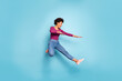 © deagreez - Full length photo of dark skin pretty wavy lady jumping high dancing modern youngster moves wear casual outfit isolated pastel blue color background