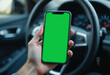 © Pixelbus - Hands holding a smartphone with a green mock-up screen inside a car, with a sharp foreground and blurred background, symbolizing technology and mobility.