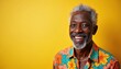 © Vadym - Happy senior african american man smiles, looks at camera. Retired elderly male wears colorful flower shirt, has gray hair and beard, expresses joy on yellow background. Positive emotion.