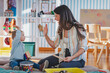 © lordn - A joyful woman and a toddler girl play with wooden educational toys in a warm, cozy playroom, fostering creativity and learning through fun activities