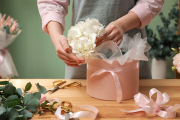 Wall Mural - Florist making beautiful bouquet at table in flower shop, closeup