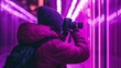 © Алексей Иванченко - A person captures a creative moment, framed in vibrant neon purple lights and warm clothing, highlighting the essence of urban photography with bold colors and artistic expression.