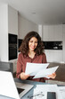 © Stock 4 You - Vertical portrait smiling young business woman working on laptop computer reading financial bills document at home office. Freelance entrepreneur manager businesswoman doing paperwork using pc remote