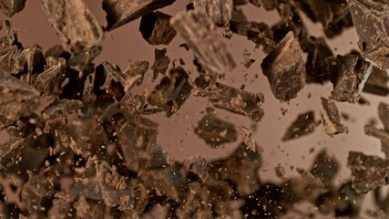 Poster - Super Slow Motion of Flying Chocolate Chunks in the Air. Isolated on Brown Background. Filmed on High Speed Cinema Camera, 1000 fps.