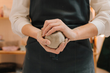 Poster - Girl potter is creating a ceramic ware in the workshop. Woman potter works with wet clay in the pottery studio.