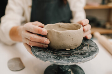 Poster - Female potter hands shows ceramic bowl ready for firing in a kiln. The process of creating ceramic products.