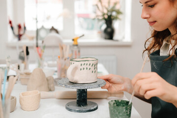 Fototapete - Artist is decorating and painting handmade ceramic clay cup in the creative workshop. Painter is drawing and adding unique designs to the earthenware.