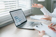 © Satori Studio - Professionals discussing financial data on a laptop in a bright office setting, emphasizing teamwork and strategy.
