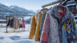 © IA Tuga - A close-up view of a variety of colorful winter coats hanging on a wooden rack against a stunning snowy mountain backdrop