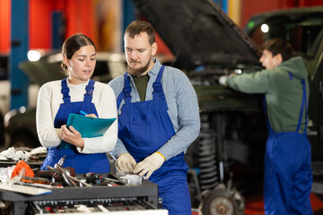 Wall Mural - Car service manager discusses car repair problems with a mechanic. He takes notes on paper