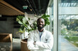 © Marko Geber - Portrait of a confident African American doctor standing with arms crossed in modern hospital