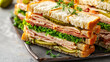 © VALUEINVESTOR - Close up of club sandwiches with turkey, lettuce, and pickles on a grey background, generative AI