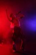 © New Africa - Talented singer performing on dark background with color lights and smoke