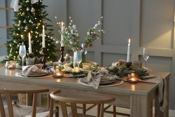 Wall Mural - Christmas table setting with stylish dishware, glasses and burning candles in festive decorated room