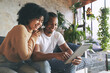 © peopleimages.com - Laugh, home and couple on sofa with tablet for internet, online shopping and streaming website. Dating, weekend and happy African man and woman on digital tech for social network, relax and connected