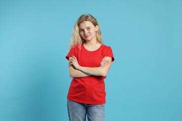 Sticker - Young woman wearing blank red t-shirt on light blue background. Mockup for design