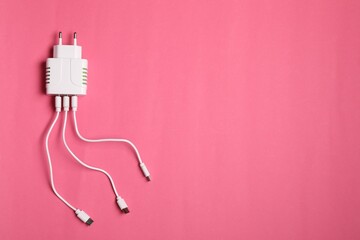 Wall Mural - USB power adapter with charge cables on pink background, top view. Space for text