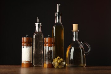 Canvas Print - Salad dressings, spices and olives on wooden table against black background