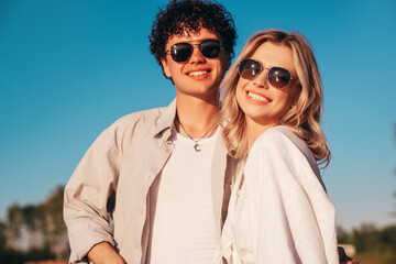 Wall Mural - Smiling beautiful woman and her handsome boyfriend. Excited couple in casual clothes. Happy cheerful family. Female and man pose at sunrise over sea beach outdoors. Seaside in summer day