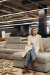 © Roman - Stylish Woman Sitting on Sofa in Modern Interior Setting