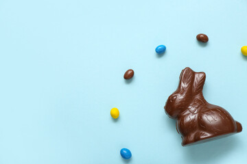 Wall Mural - Chocolate Easter bunny and candies on blue background