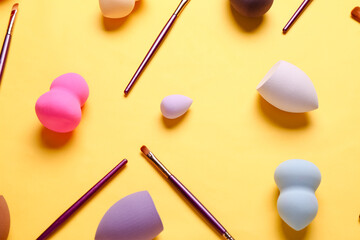 Wall Mural - Makeup sponges and brushes on yellow background