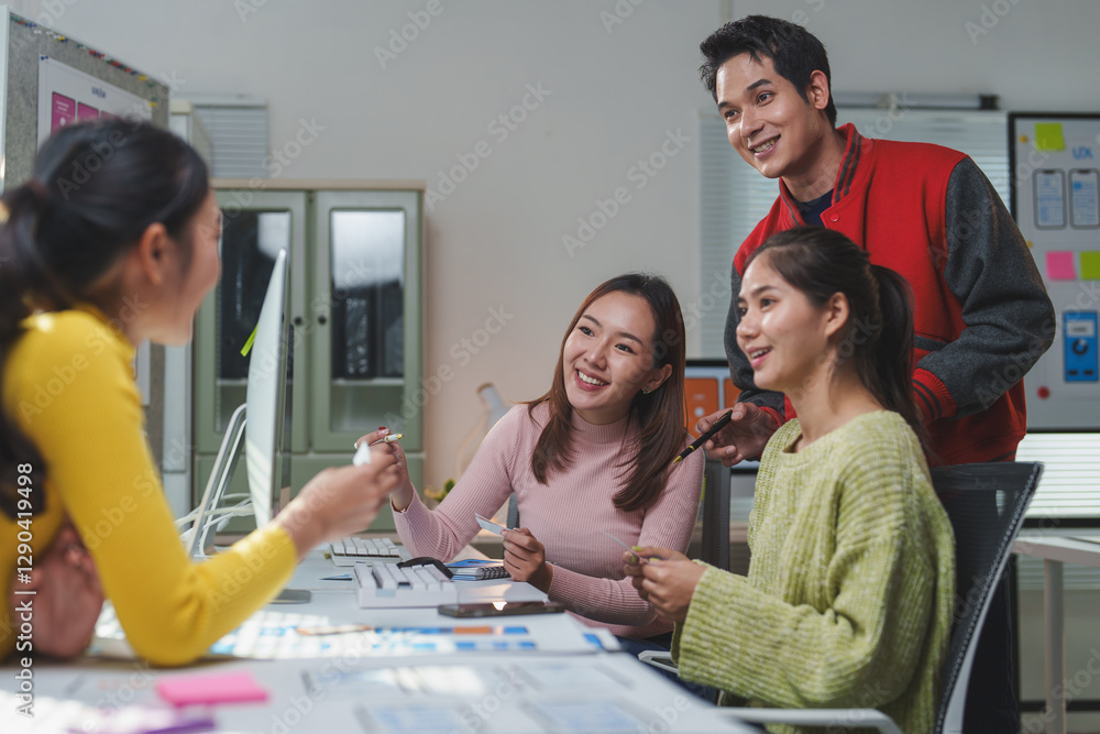 Four asian web designers discussing a new project in front of a ...